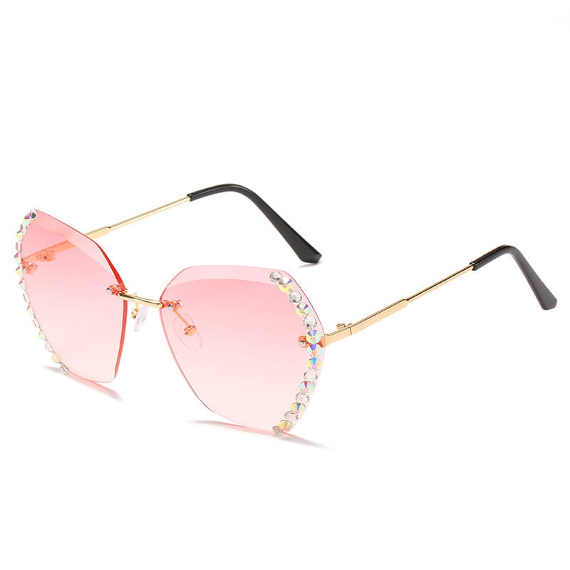 Diamond studded rimless polygonal gradient sunglasses featuring pink gradient lenses with gold tone frames and sparkling rhinestone embellishments along the edges.