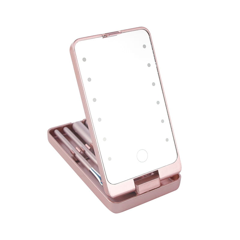 Rose gold framed LED makeup mirror with built-in stand and folding brush set case holding makeup brushes.
