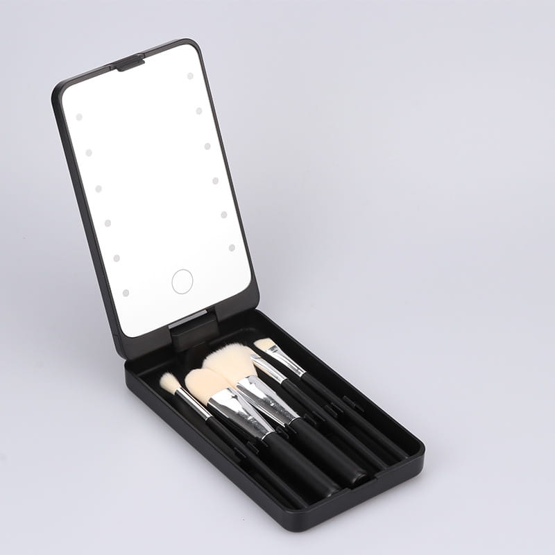 Black compact led makeup mirror with folding brush set case featuring illuminated LED lights and included makeup brushes inside for convenient beauty application.