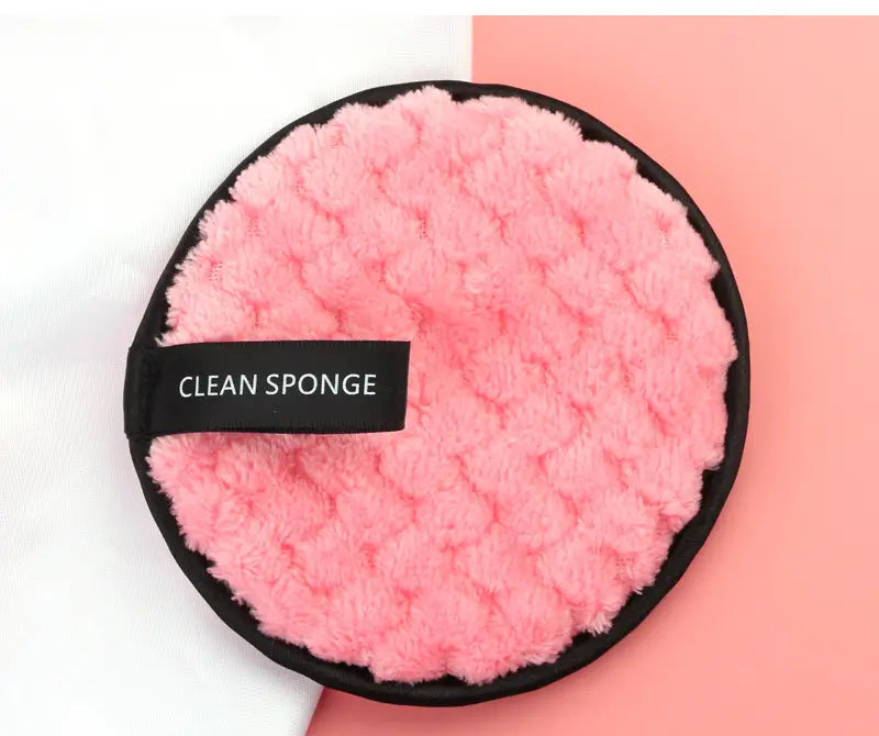 a pink fluffy textured clean sponge with a black border and label for makeup removing puff 3 pack with mesh bag