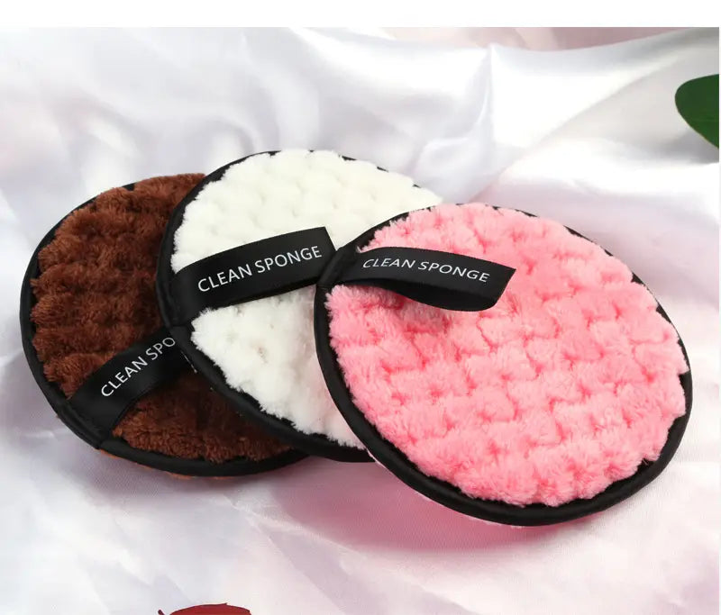 makeup removing puff 3 pack featuring three circular plush sponges in brown white and pink with black trim and matching labels designed for gentle facial cleansing.