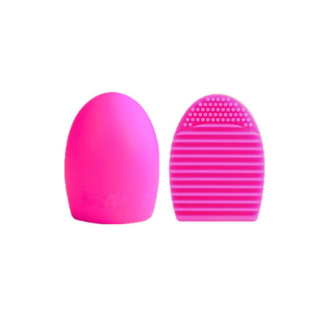 Bright pink silicone makeup brush cleaner egg scrubbing tool with a smooth rounded handle and textured ridged head for gentle eyelash brush application.
