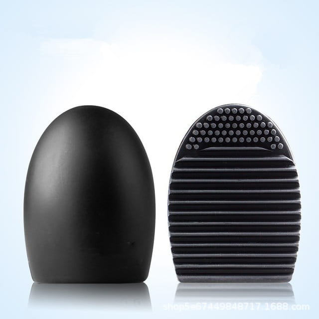 Black egg-shaped makeup brush cleaner with textured bristles and smooth silicone handle for effective eyelash brush scrubbing.
