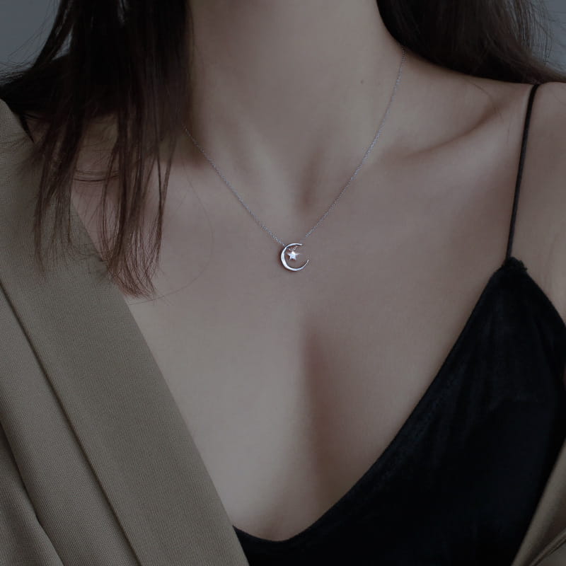 Sterling silver crescent moon and star pendant necklace featuring a delicate silver crescent moon with a small star embedded in its center.