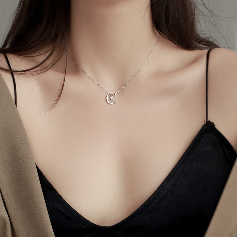 A delicate sterling silver necklace featuring a crescent moon pendant with a small star embedded within it.