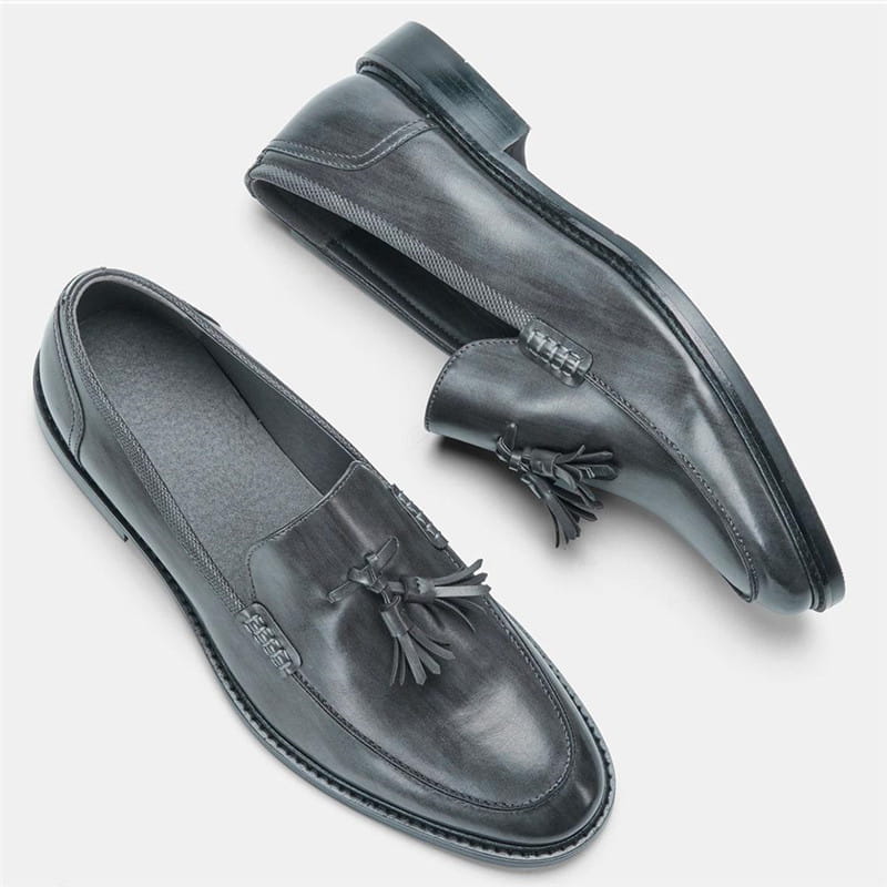 Men’s polished leather tassel loafers in black with a polished finish and subtle stitching details featuring composite soles.