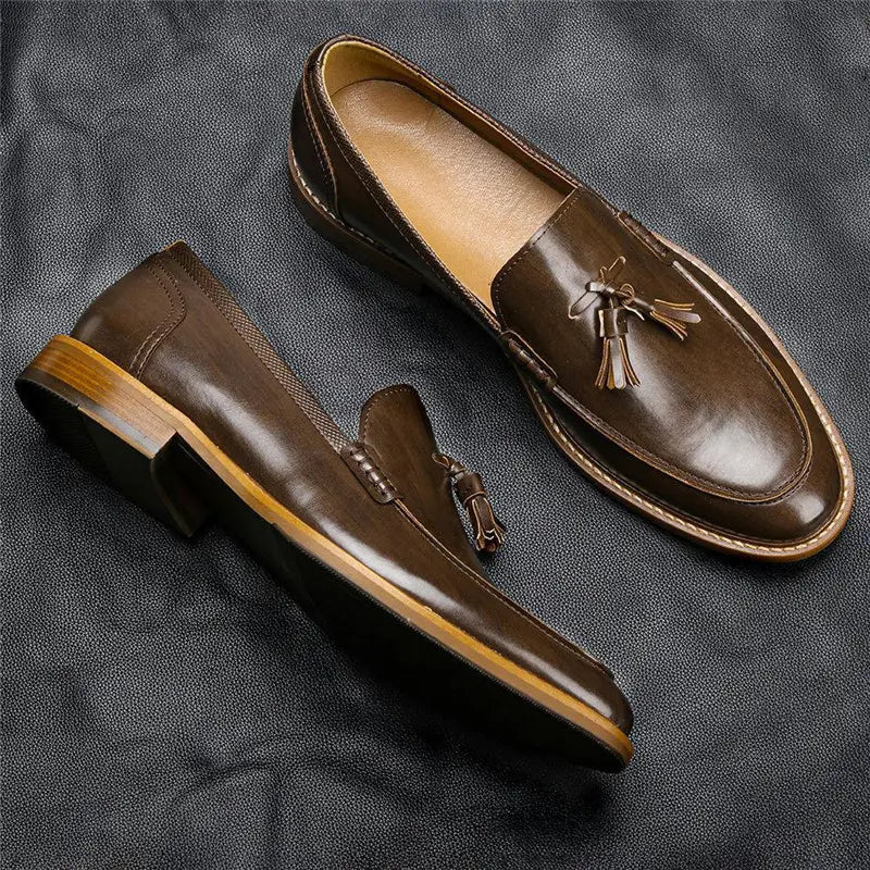 Men’s polished brown leather tassel loafers with a polished finish and light-colored composite soles.