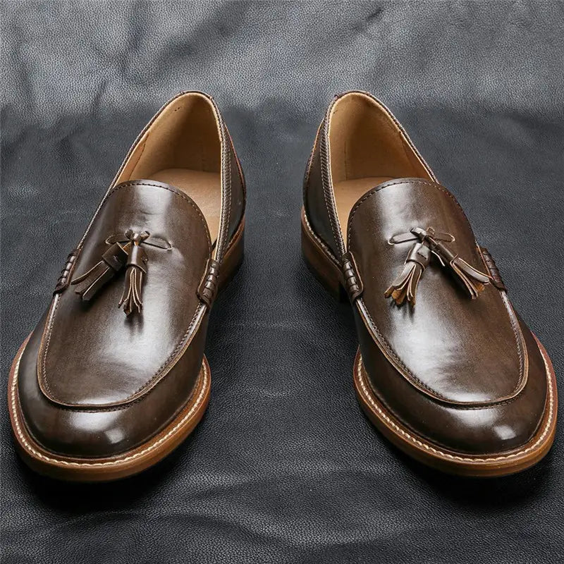 Men’s polished brown leather tassel loafers with a polished finish, contrasting tan stitching, and composite soles.