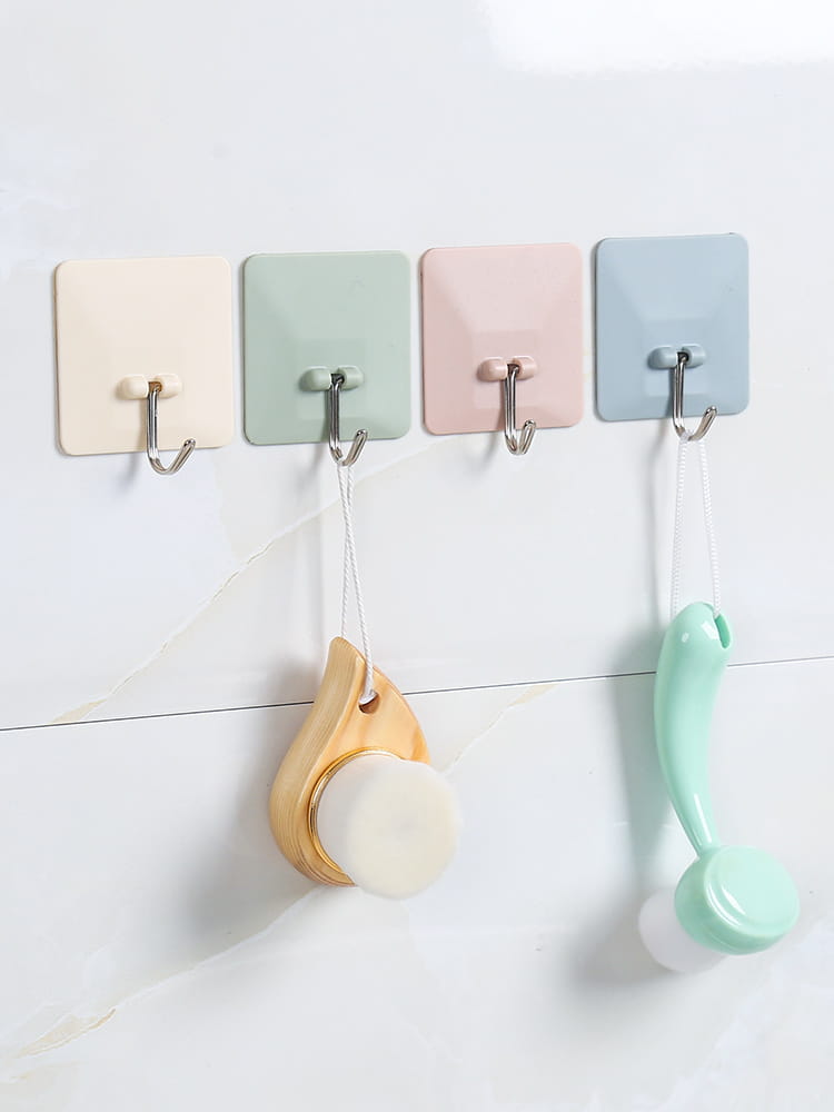 Quatre crochets muraux adhésifs imperméables avec des crochets en forme de J métalliques argentés dans des tons pastel crème, vert menthe, rose poudré et bleu clair, pour un montage mural polyvalent.