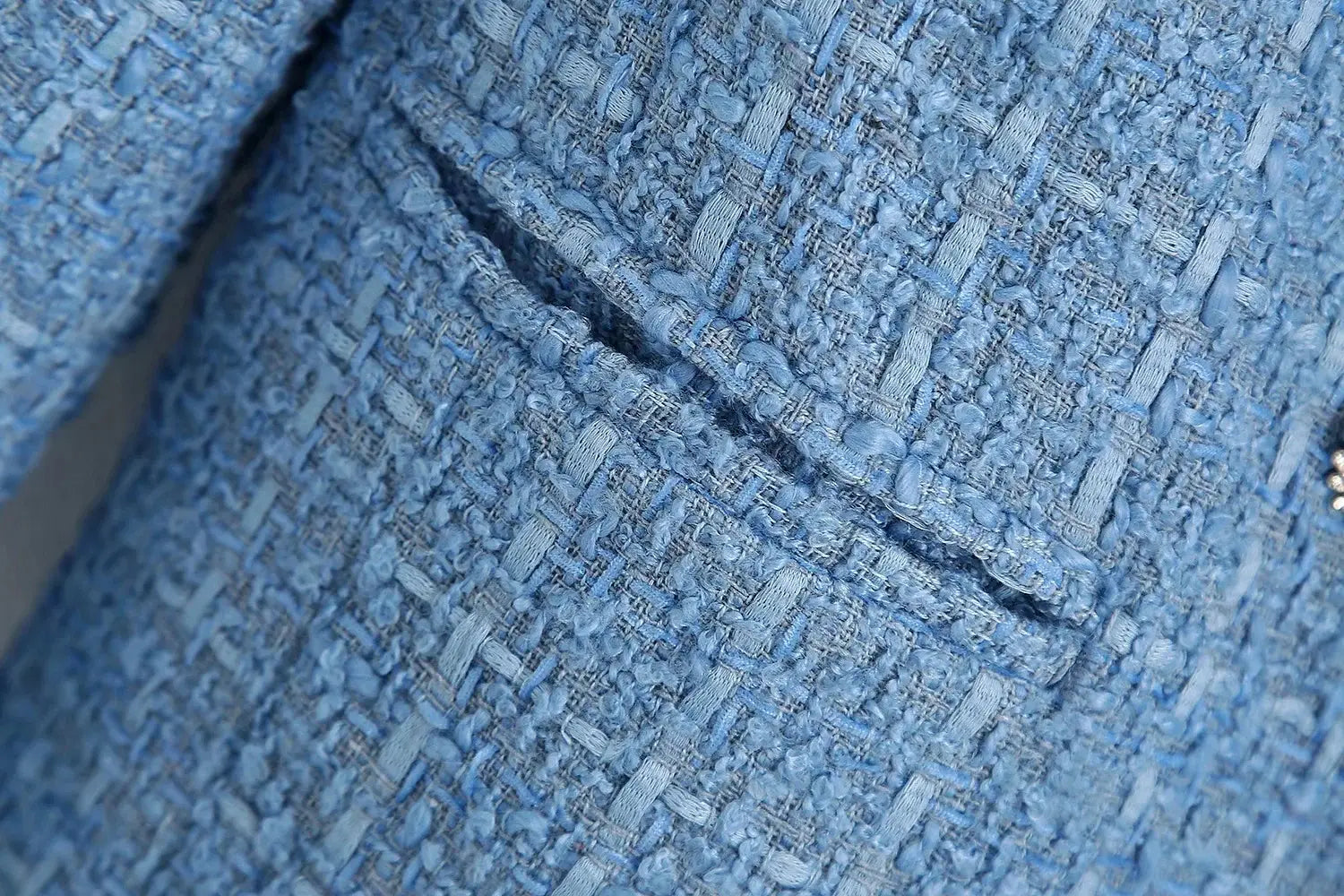 Women’s double breasted light blue textured tweed blazer featuring a subtle woven pattern and a small decorative button.