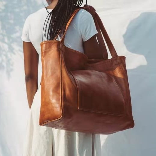 A large capacity oil wax leather tote shoulder bag made of rich tan leather with sturdy handles and a minimalist design.