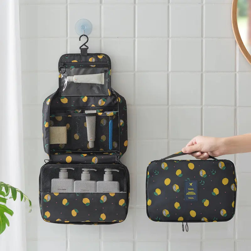 Schwarze Kosmetiktasche mit Zitronenmuster, mit mehreren Fächern und einem als Aufhängehaken gestalteten Haken, ausgelegt als hängender Kulturbeutel-Organizer für Reise-Make-up.