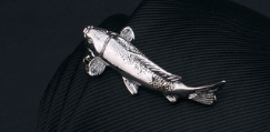Silver fish-shaped lapel pin with detailed scales and fins in polished metallic finish from men’s airplane tie clip and lapel pin gift set.