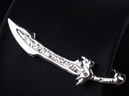 Silver sword-shaped pendant with intricate engraved details and decorative hilt featured in a men’s airplane tie clip and lapel pin gift set.