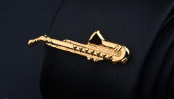Gold-colored saxophone-shaped tie clip made of metal featured in the men’s airplane tie clip and lapel pin gift set.