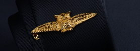 Golden bat-shaped pin with intricate wing detailing crafted from metallic material in a men’s airplane tie clip and lapel pin gift set.