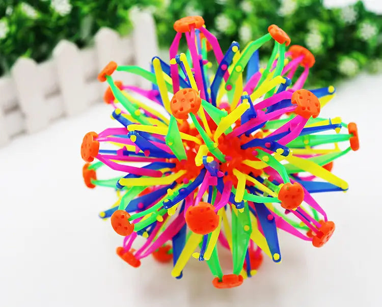 Jouet de balle magique à expansion en forme de sphère télescopique multicolore et éclatant, doté de pointes en plastique rose fluo, vert, jaune et bleu, avec des capuchons orange, dans une conception de sphère télescopique.