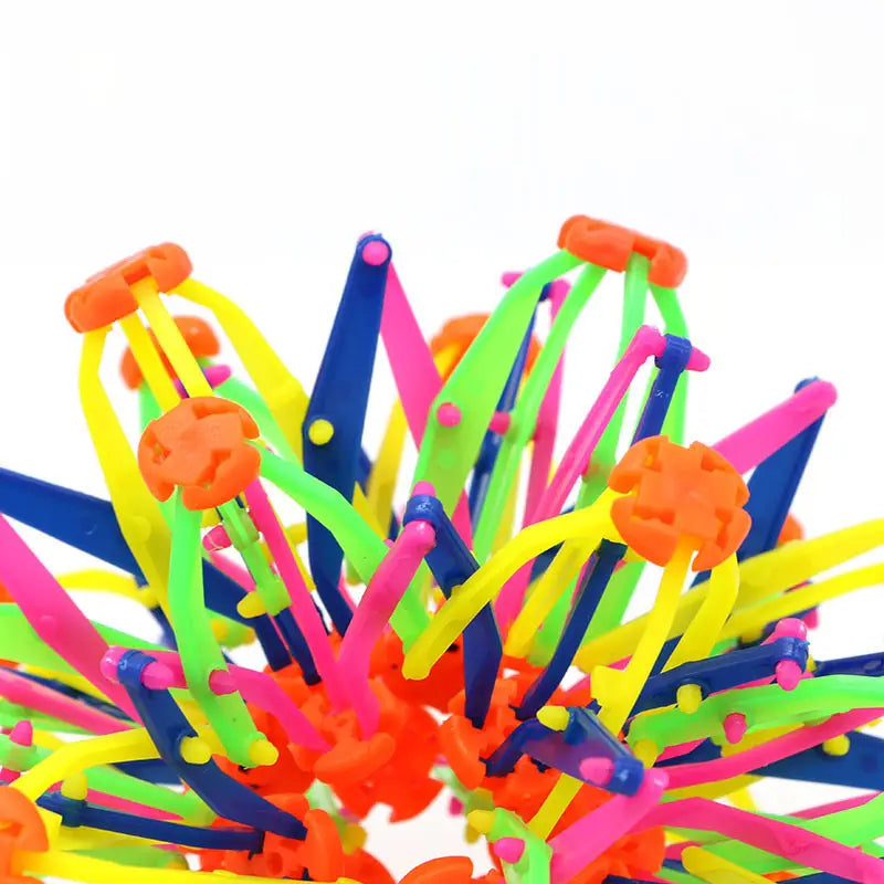 Jouet de balle magique à expansion, sphère télescopique colorée, fabriqué en plastique néon vibrant, avec une texture épineuse et des connecteurs orange et bleu.