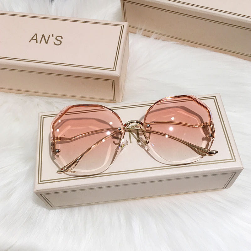 Sonnenbrille mit übergroßem, geometrischem Metallrahmen und Gradient, mit Roségold-Metallgestellen und Gradienten-Pinklinsen.