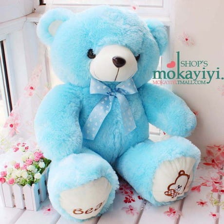 A soft light blue plush teddy bear with a white snout and black button eyes wearing a matching bow tie plush animal doll.