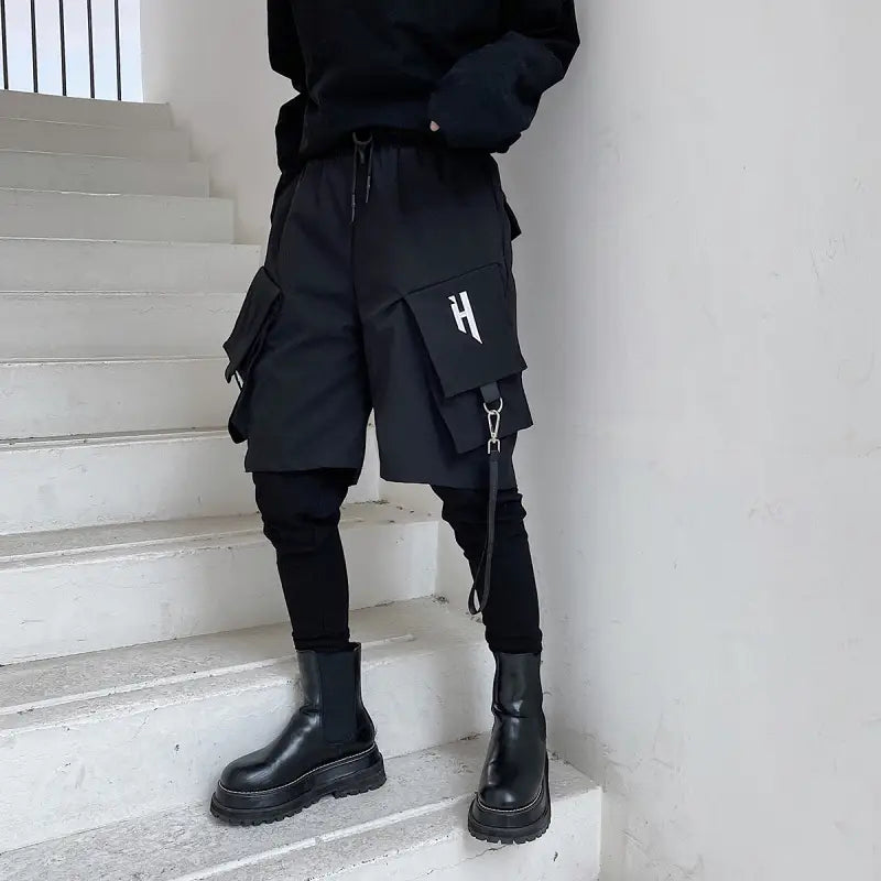 black cargo shorts with multiple pockets and detachable strap featuring a white h logo on the thigh pocket designed as hip hop pants