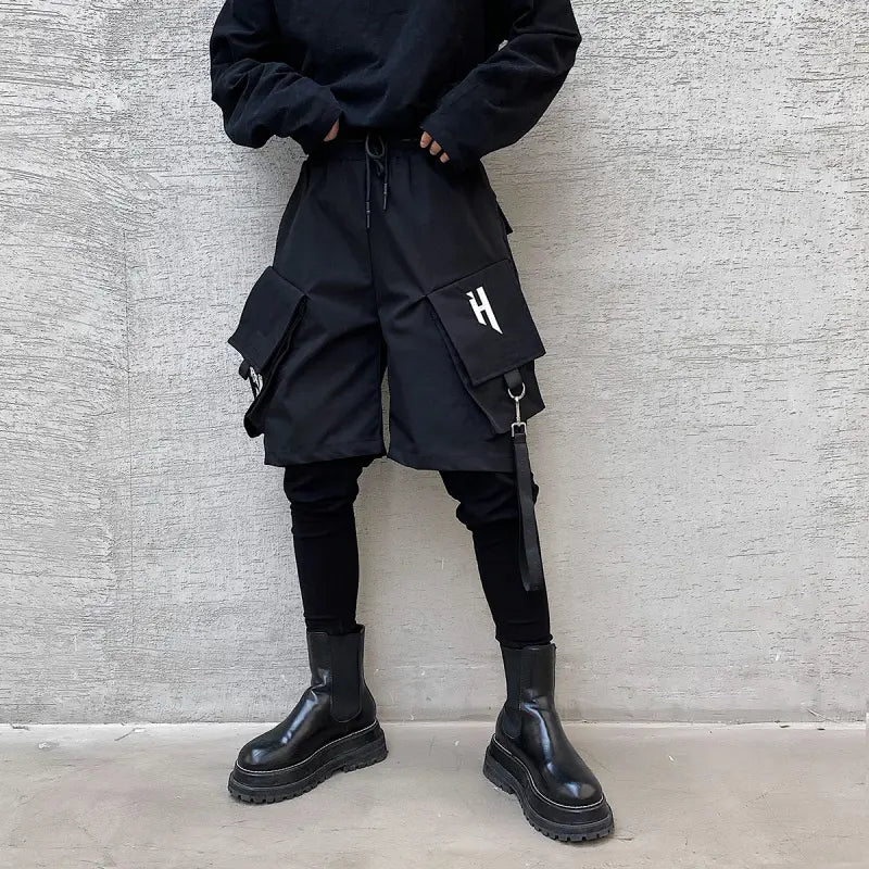 Black cargo shorts with multiple pockets and a white logo on the thigh featuring detachable straps designed for hip hop style.