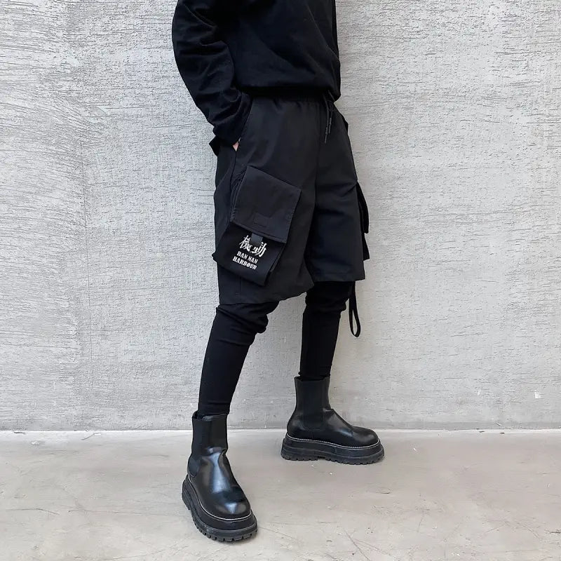 Black cargo shorts with multiple pockets and a detachable strap feature white text patch suitable for hip hop style pants.