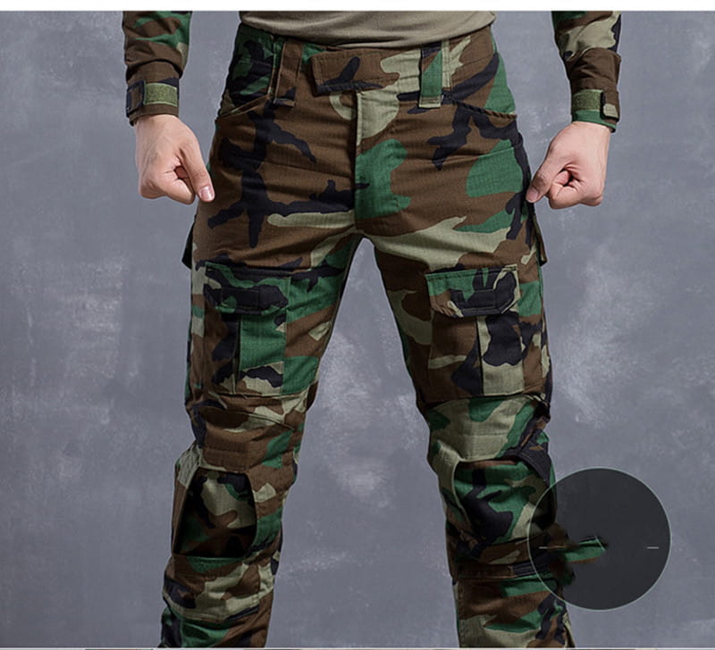 Pantalon tactique avec genouillères et poches cargo dans un motif camouflage de type woodland vert, brun et noir, conçu pour un usage militaire et en extérieur.