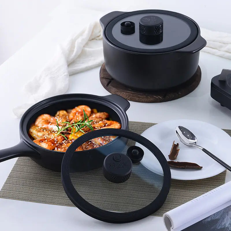 Black ceramic micro pressure anti overflow casserole pot with glass lid, black knob, and two handles for easy handling.