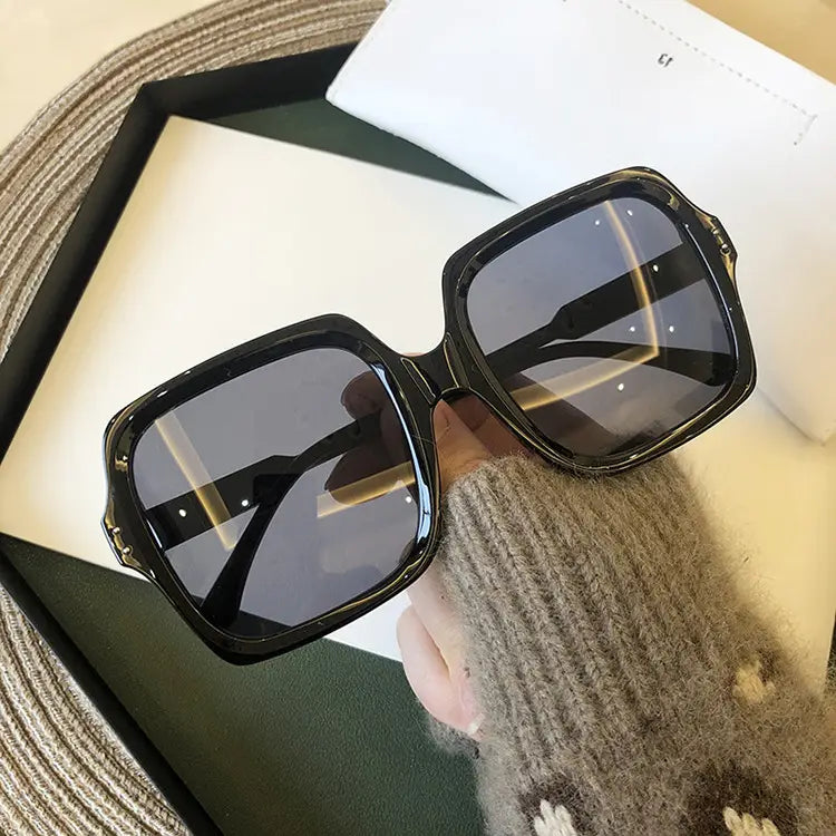 oversized square fashion sunglasses featuring black square-framed translucent frames with dark gray lenses and a glossy finish