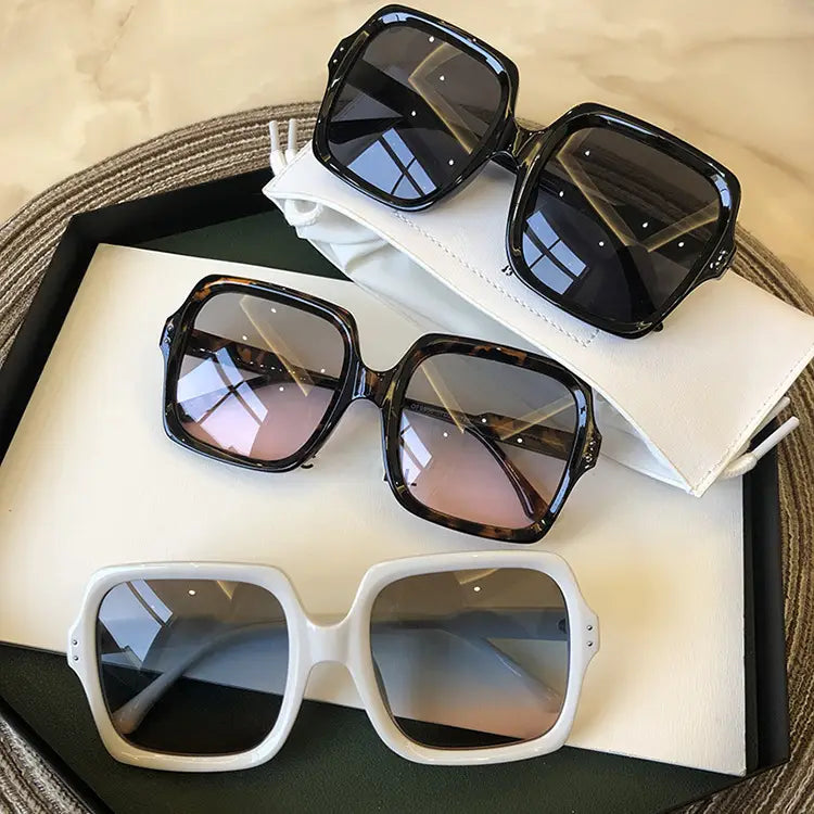 Oversized square fashion sunglasses with translucent black tortoiseshell and white frames featuring gradient lenses.