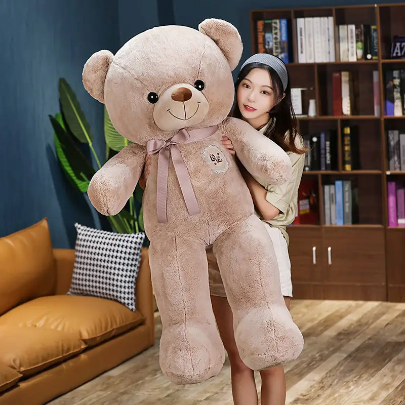 Ein kuscheliger beiger Teddybär mit weicher Fellstruktur und bestickten Gesichtszügen, der für Kinder und Mädchen mit einem Liebesband ausgestattet ist.