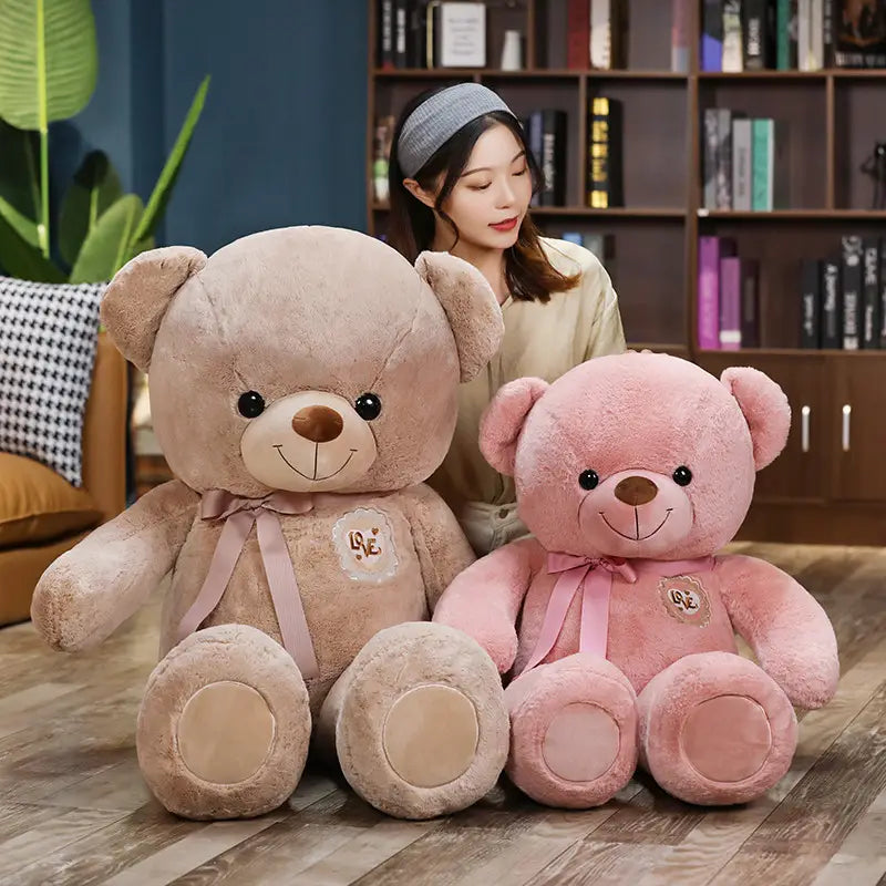 Weiche beiger und rosafarbene Stoff-Teddybären mit bestickten Liebes-Patches und passenden Bändern, entworfen für Kinder und Mädchen.