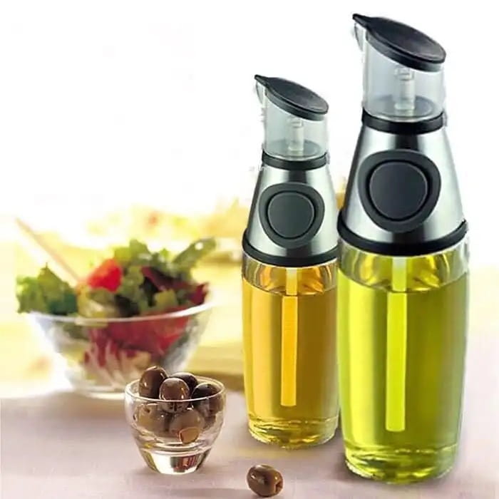 Deux distributeurs d’huile en verre transparent munis de tasses de mesure de précision remplies d’une huile d’olive jaune doré, avec des touches noires et argentées.