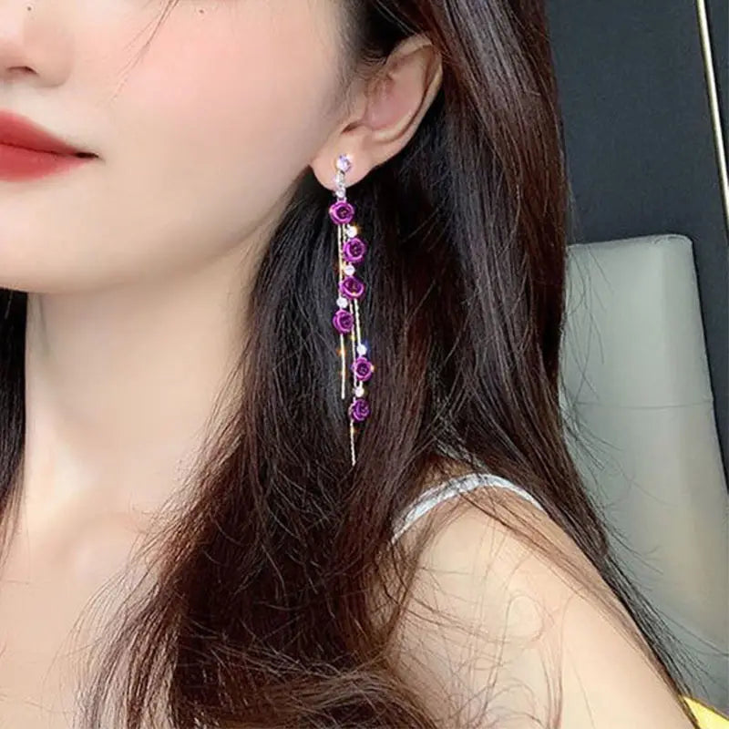 Elegant rose tassel drop earrings feature purple rose-themed design with sparkling crystal rhinestones and pearl accents.