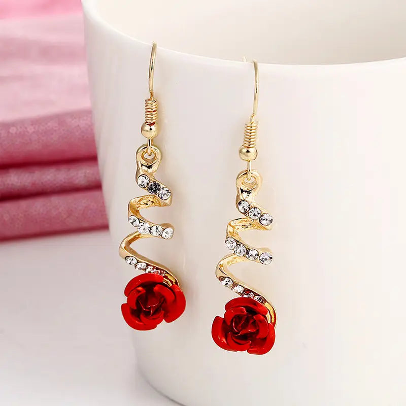 Gold-toned elegant rose tassel drop earrings featuring spiral design with clear rhinestones and vibrant red rose charms.