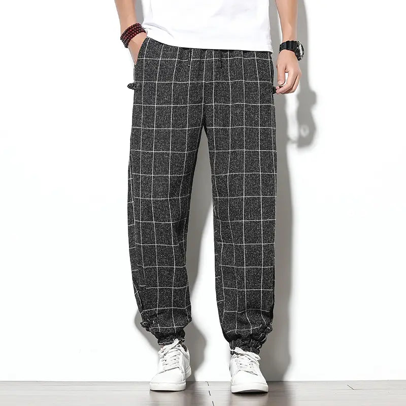 Men plaid harem pants featuring a black and white checkered herringbone pattern with elastic cuffs designed as loose casual cropped trousers.