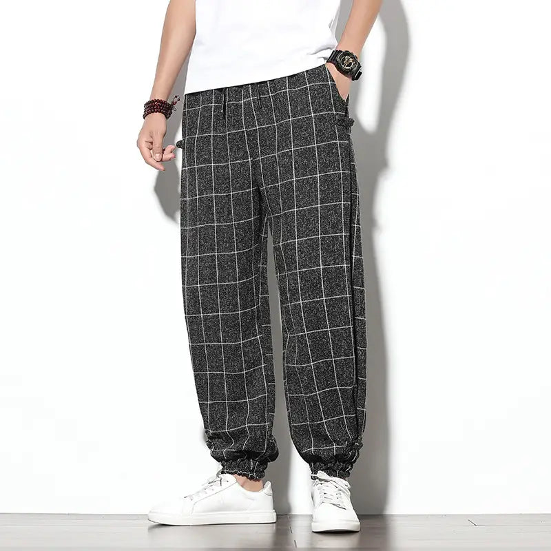 Men plaid harem pants in black and white checkered pattern featuring a loose tapered fit ideal for casual wear.
