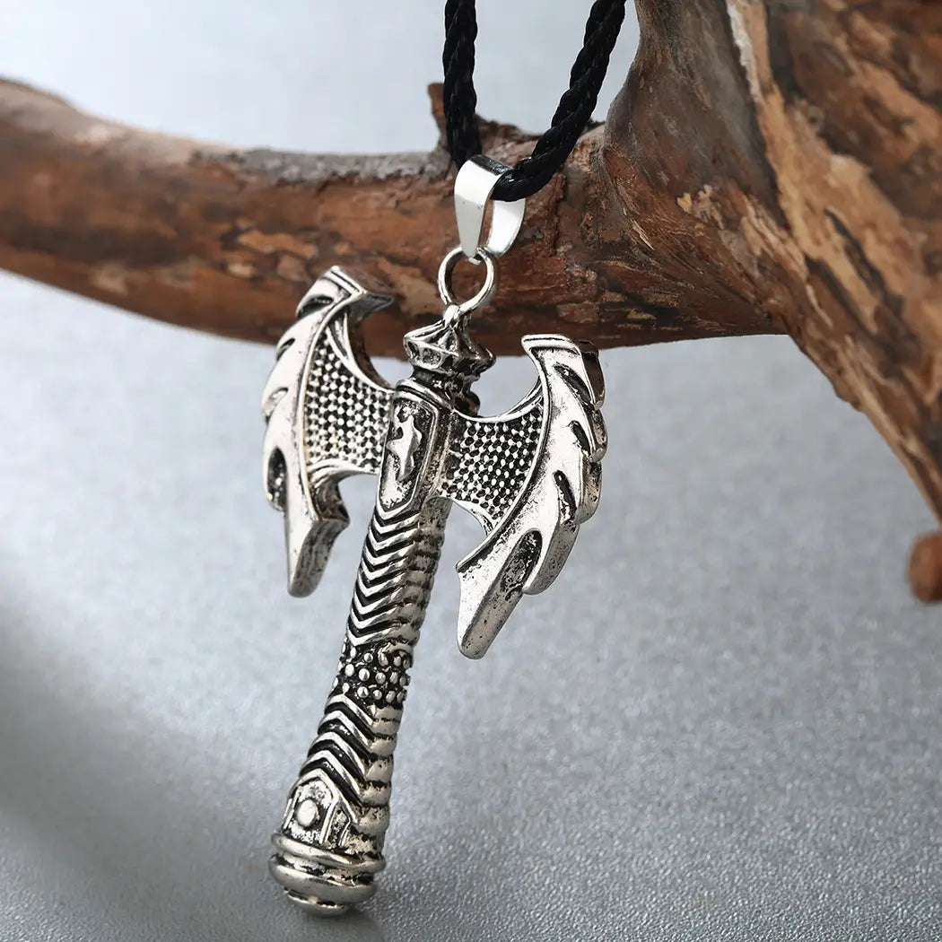 Intricate Viking axe pendant necklace featuring a silver-colored, intricately detailed double-headed axe pendant hanging from a black braided cord.