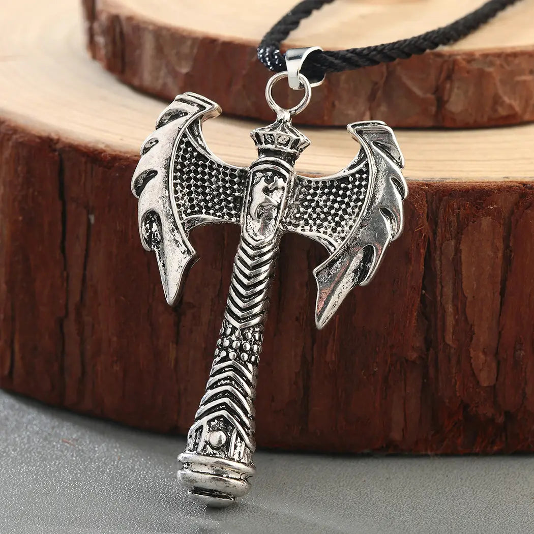 Intricate viking axe pendant necklace in silver with engraved details and black braided cord.