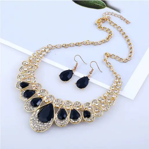 Vintage gold teardrop crystal bridal jewelry set featuring a gold-toned necklace with black teardrop-shaped stones and sparkling clear crystals in an ornate layered design.