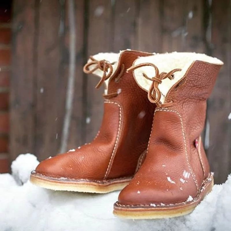 Brown leather women’s shearling lined leather martin boots with cream-colored shearling lining, matching laces, and visible stitching along the seams.