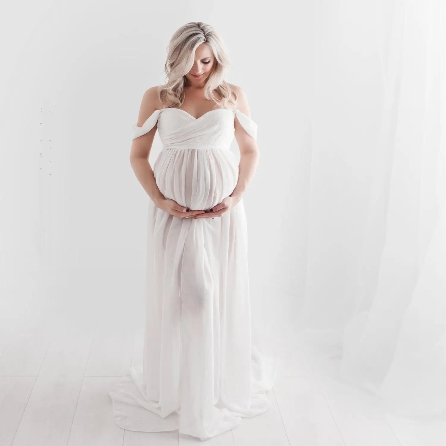 a flowing off the shoulder white chiffon maternity gown with a draped bodice and soft airy fabric designed for photoshoots