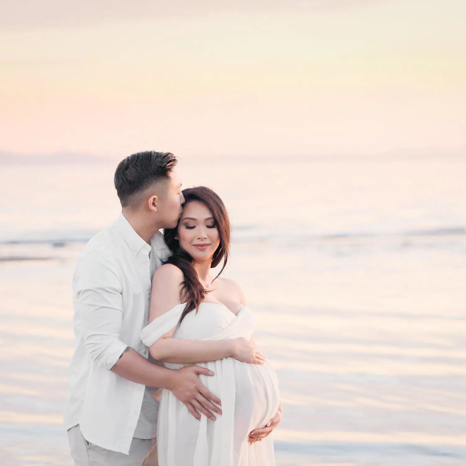 A flowing white chiffon off the shoulder maternity gown with soft draped silhouette designed for photoshoots.
