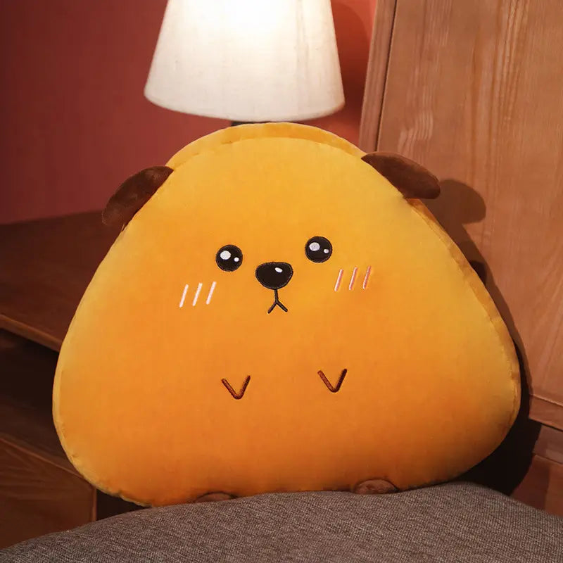 Ein weiches, dreieckig geformtes orangefarbenes Kuscheltier-Kissen, mit bestickten schwarzen Augen und einer Nase sowie braunen Stoffohren und angenähten Schnurrhaaren, die einem Kaninchen, Schwein oder Huhn ähneln.