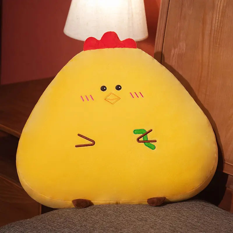 Ein gelbes Kuschel-Huhn-Kissen mit rotem Kamm, bestickten schwarzen Augen, Wangen und Schnabel; mit grün und braun genähten Füßen; weiches Tierkissen für Wohnraumdekoration und Komfort.
