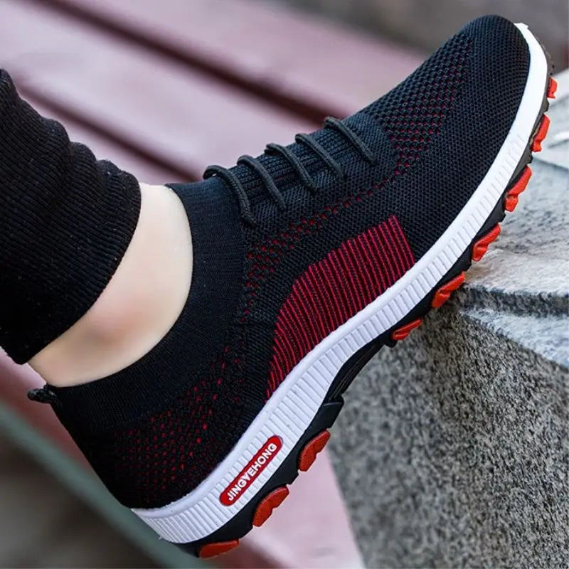 Herren-Strickatmungsaktive Freizeitsportschuhe mit einem schwarz-rot geflochtenen Obermaterial, einer weißen Zwischensohle und einer orangefarbenen Gummiaußensohle.