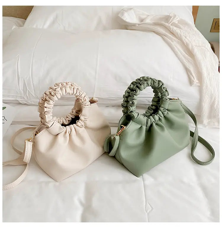 Beige and sage green ruched leather bucket bags with adjustable straps and elasticated drawstring handles.