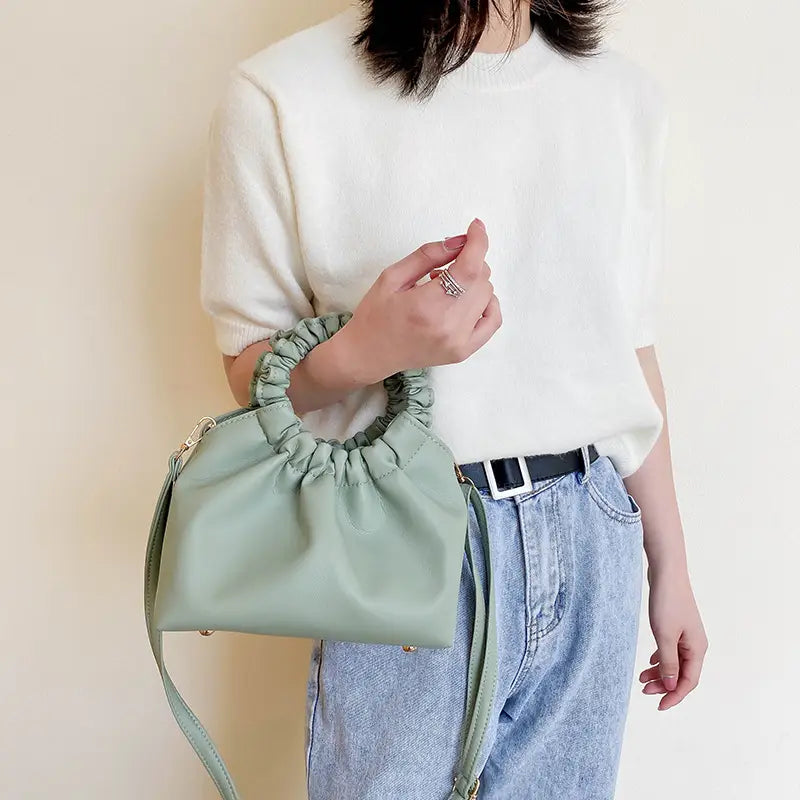 Mint green ruched leather bucket bag made of faux leather with a gathered elasticated top handle and matching adjustable strap.