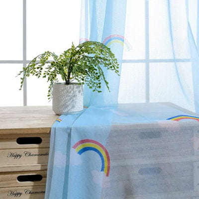 Light blue tablecloth with a colorful rainbow print paired with rainbow blackout and sheer curtains for kids room.